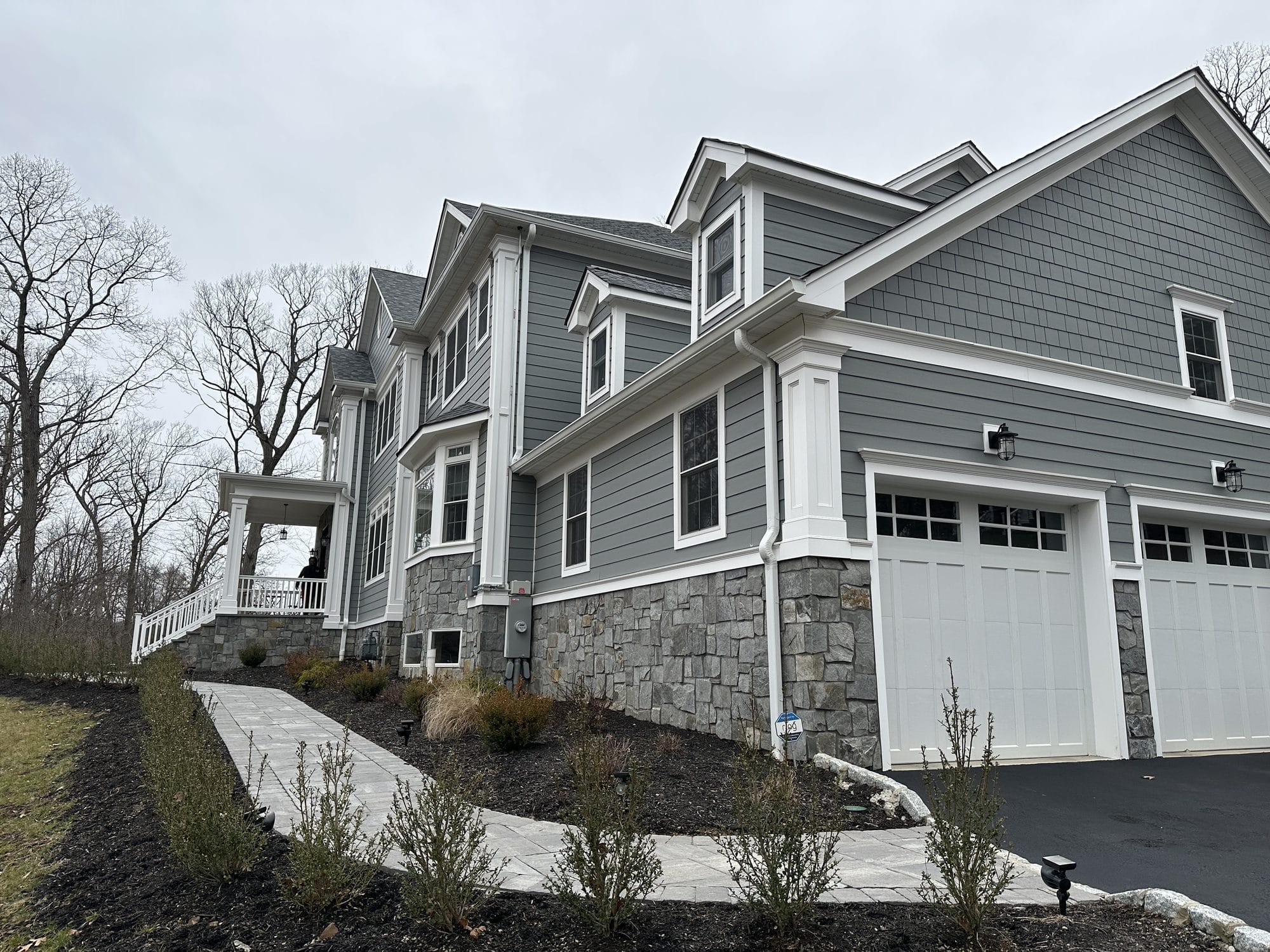 Craftsman home side elevation with natural stone base and carriage-style garage doors