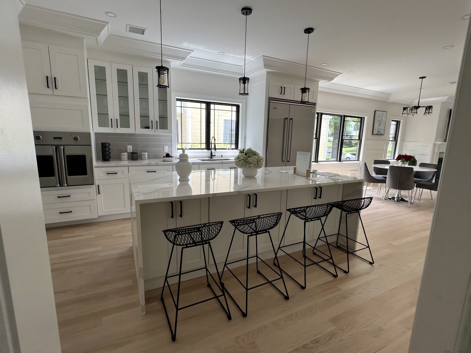 Kitchen with Calacatta island and wire bar stools, seen through a cased opening