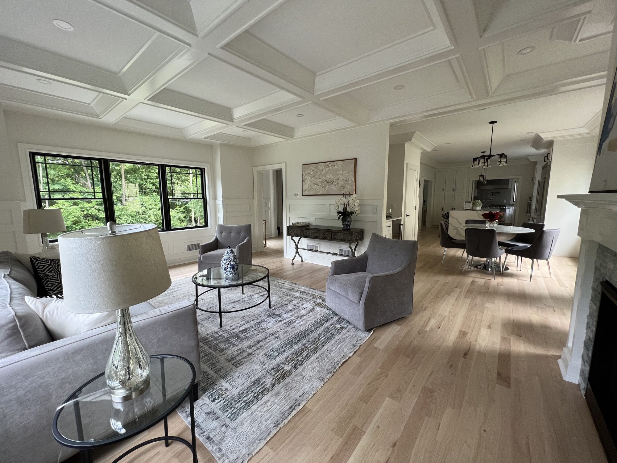 Staged living room with coffered ceiling opening to the dining area