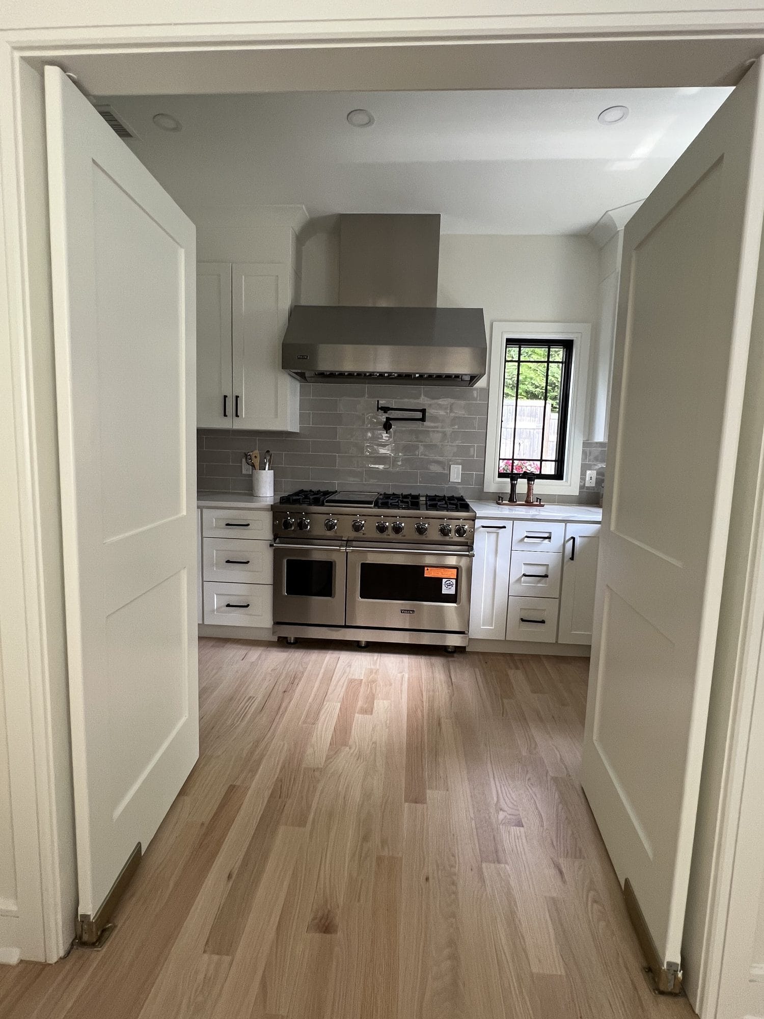 Scullery prep kitchen with professional range and pot filler, seen through double doors