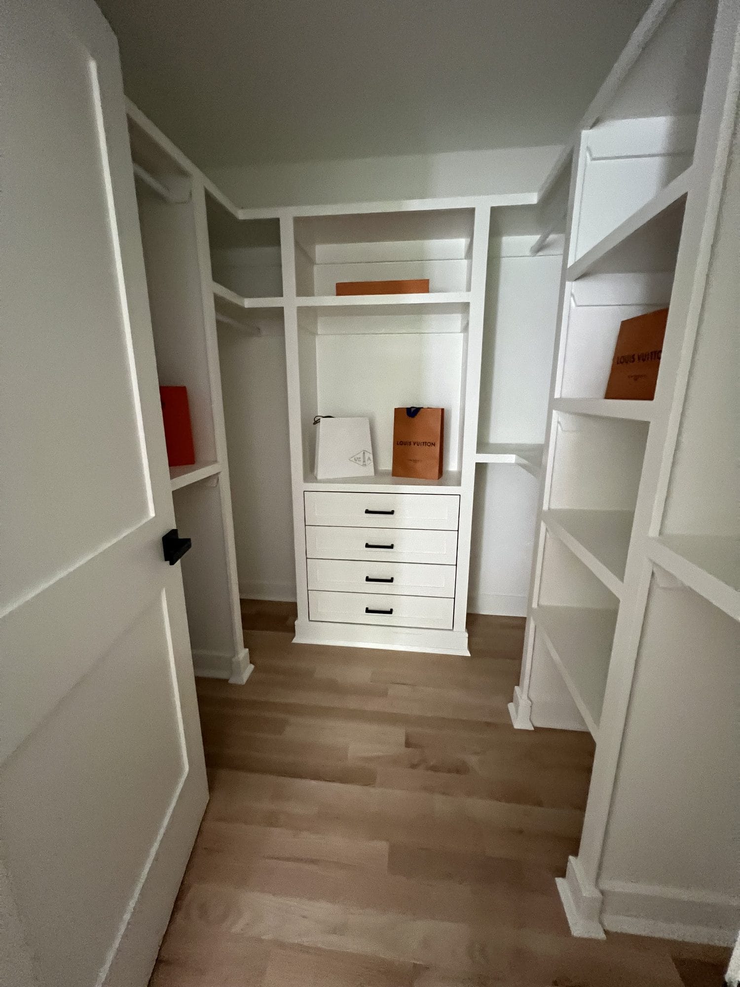 Walk-in closet with custom white built-ins and shelving